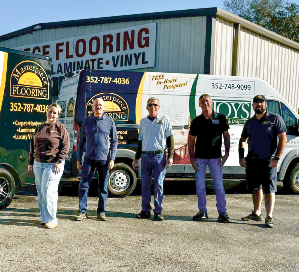 The Masterpiece Flooring Team standing in front of vans and office building.