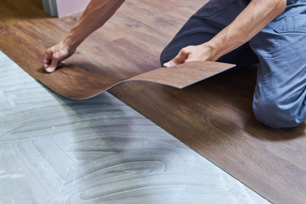Worker joining vinyl floor covering at home renovation.